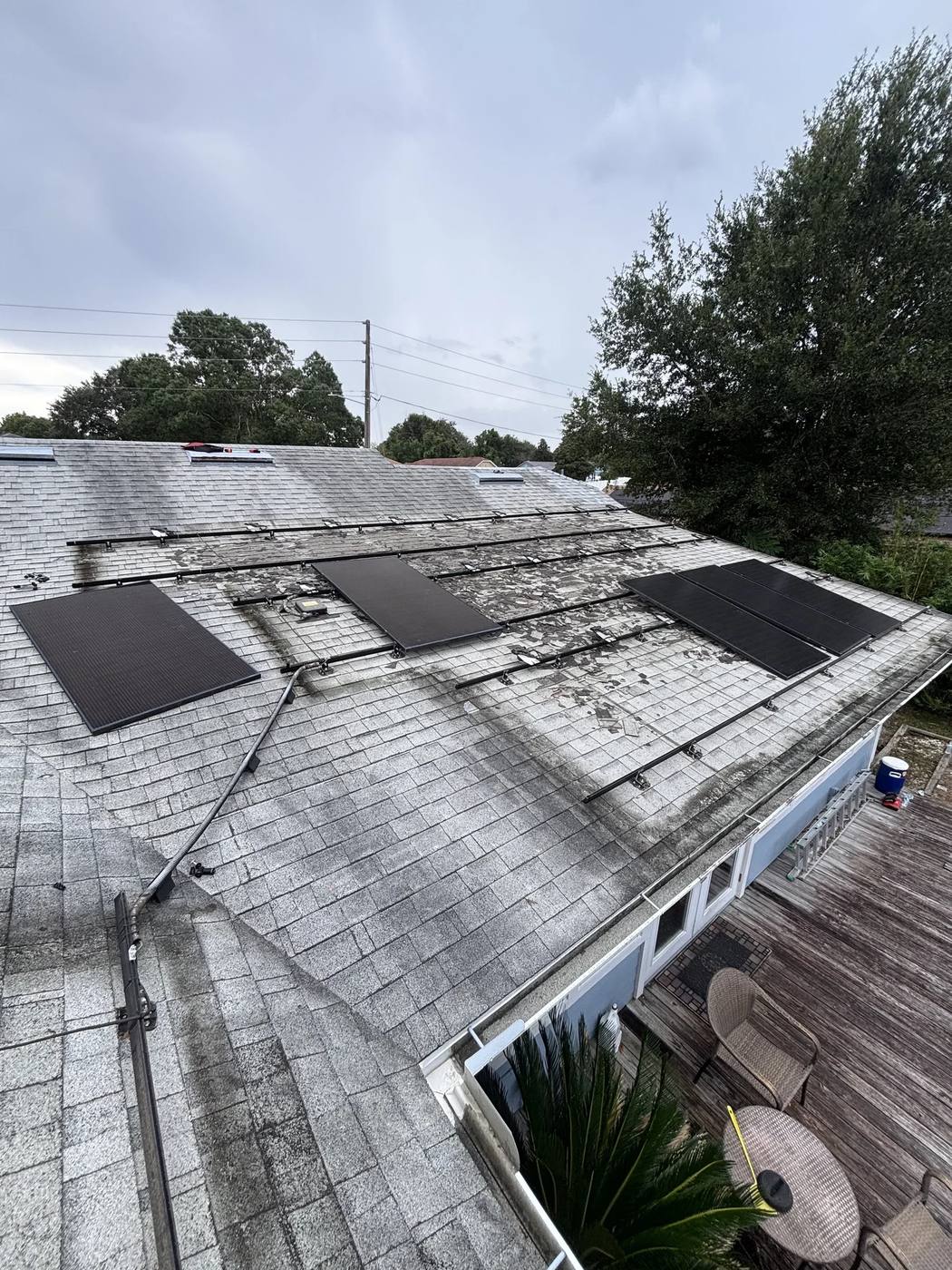 Stained shingle roof with most panels removed and the mounting rails exposed
